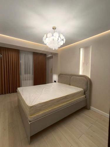 a bedroom with a large bed and a chandelier at Life park Osh 2 in Osh
