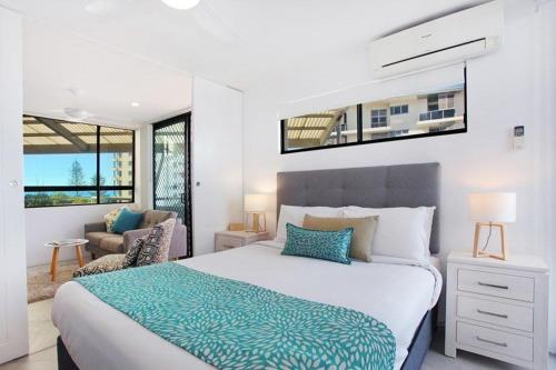 a bedroom with a large bed and a couch at Beach Club Resort Mooloolaba in Mooloolaba