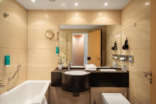 a bathroom with a tub and a sink and a bath tub at Atrium Hotel Krüger in Rostock