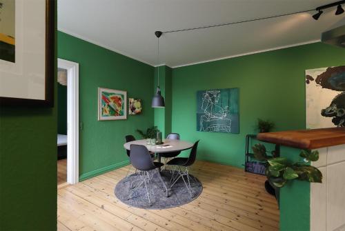 a dining room with green walls and a table and chairs at Greenbrook Homes - Family 7PPL in Aalborg
