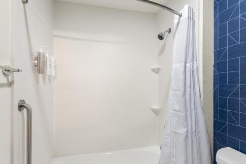 a bathroom with a shower with a white shower curtain at Spark by Hilton Matteson Chicago I 57 in Matteson