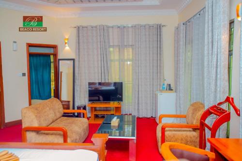 ein Wohnzimmer mit zwei Stühlen und einem Fernseher in der Unterkunft Beaco Resort in Mbeya