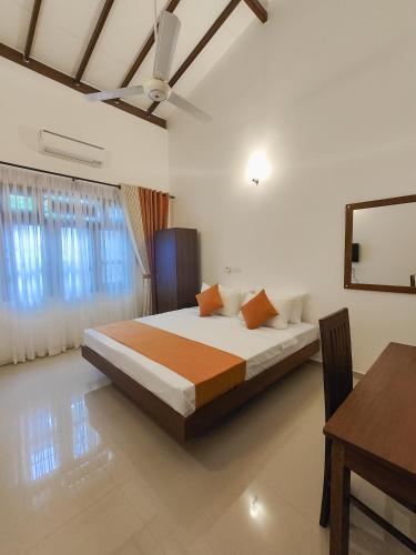 a bedroom with a bed and a desk and a table at Shalom Resort in Avissawella
