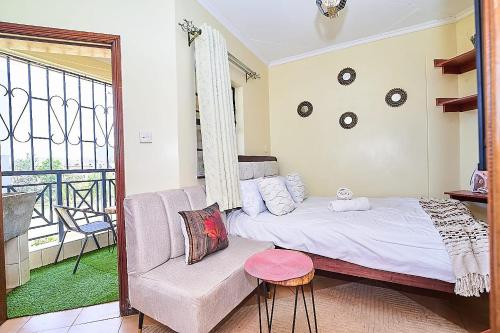 a bedroom with a bed and a couch and a window at GoldKent Kileleshwa in Gatunga