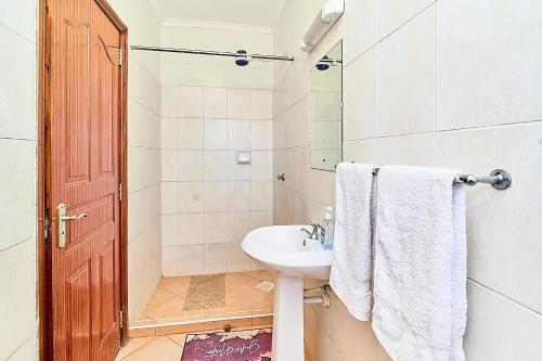 a white bathroom with a sink and a shower at GoldKent Kileleshwa in Gatunga