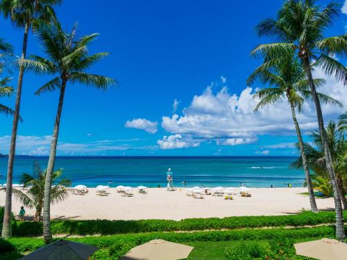a beach with palm trees and the ocean at HOTEL MOON BEACH MUSEUM RESORT in Onna