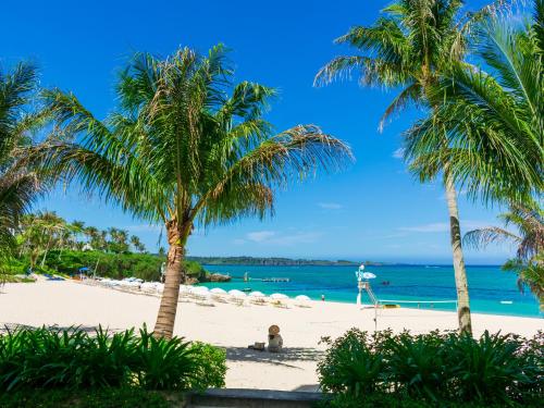a beach with palm trees and the ocean at HOTEL MOON BEACH MUSEUM RESORT in Onna
