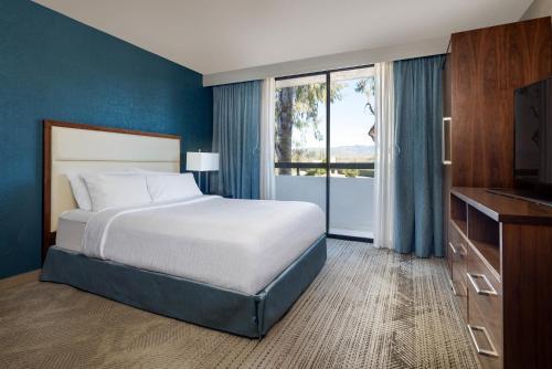 a bedroom with a bed and a large window at Embassy Suites San Luis Obispo in San Luis Obispo