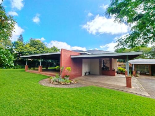 a red brick house with a green lawn at Zu Hause in Piet Retief