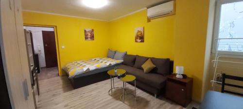 a living room with a couch and a yellow wall at Студио in Shumen