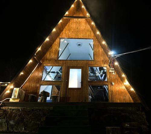 a wooden house with lights on it at night at Căsuța de pe Vale in Sighetu Marmaţiei
