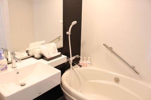 a white bathroom with a sink and a bath tub at Hotel Osaka Castle in Osaka