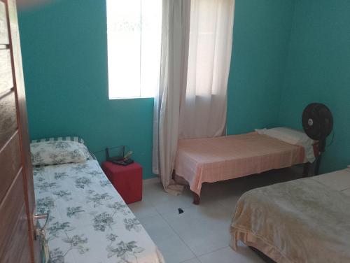 a small room with two beds and a window at Casa linda buzios in Búzios