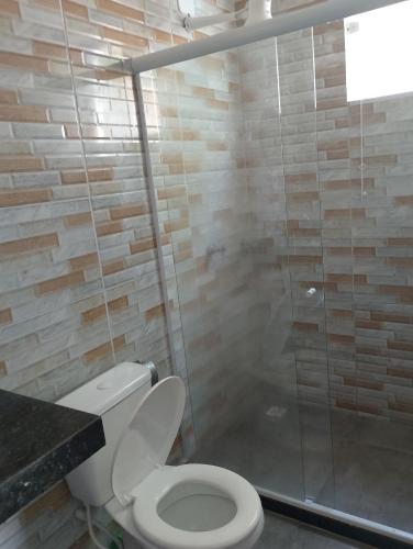 a bathroom with a toilet and a glass shower at Casa linda buzios in Búzios