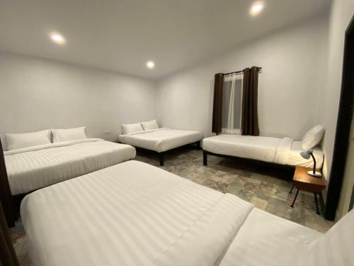 a hotel room with three beds and a chair at สวนธรรมคยา in Ban Dan Chang