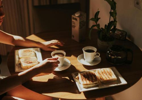 a woman sitting at a table with sandwiches and cups of coffee at のあそびlodge in Arao