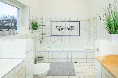 a white bathroom with a tub and a toilet at Wellnessoase mit Sauna und Garten in Würzburg