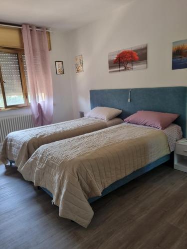 ein Schlafzimmer mit zwei Betten und rosa Kissen in der Unterkunft Affittacamere Ely in San Giórgio di Nogaro