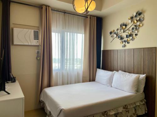 a bed in a hotel room with a window at A city escape at the Avida Towers Aspira 1 in Cagayan de Oro