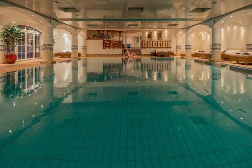 an indoor swimming pool with green tiles on the floor at Grand Hôtel du Golf & Palace in Crans-Montana