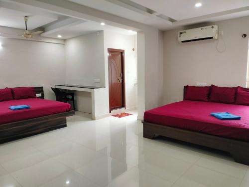two beds in a white room with red sheets at Hotel Jaganmatha Kollur in Kollūru