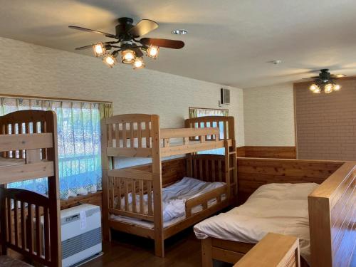 two bunk beds in a room with a ceiling fan at みんなの家ポレポレ in Urugi