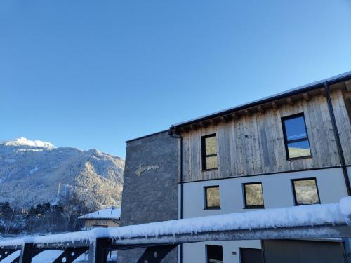 a building covered in snow with mountains in the background at Aenna Apart Prutz in Prutz