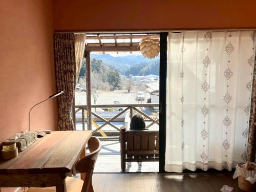 a dining room with a table and a large window at みんなの家ポレポレ in Urugi