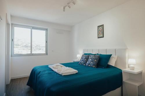 a bedroom with a blue bed with a window at Atlantic Residence Pool & Ocean View in Câmara de Lobos