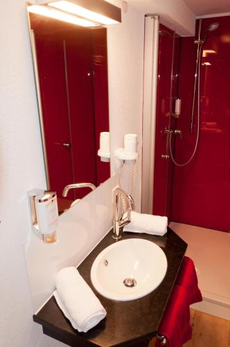 a bathroom with a sink and a red shower at BB Blick Hotel und Café in Bad Bellingen