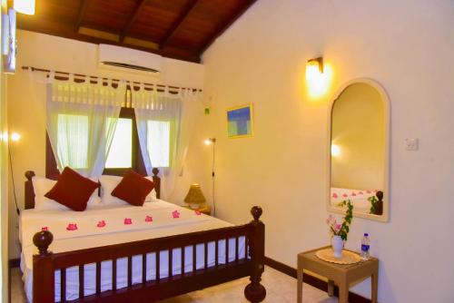 a bedroom with a large bed and a mirror at Niko Villa in Kosgoda