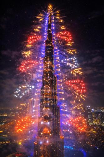 a view of the empire state building lit up at night at Private Room in Premium Burj Vista Downtown Apartment with Burj Khalifa View in Dubai