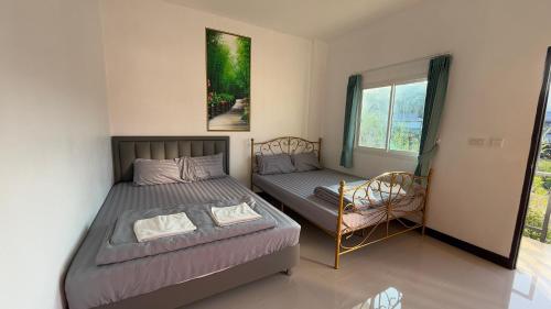 a bedroom with a bed and a chair and a window at Malee Guesthouse in Ban Rak Thai