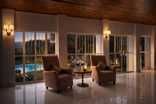 a living room with two chairs and a table and windows at La Dukes Resort in Bushman Rock
