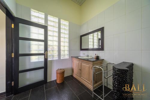 a bathroom with a sink and a mirror and a door at Villa Burung, Bali - Breathtaking oceanfront, infinity pool in Tegallengah
