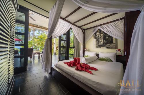a bedroom with a bed with a red bow on it at Villa Burung, Bali - Breathtaking oceanfront, infinity pool in Tegallengah