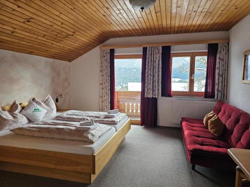 a bedroom with a bed and a red couch at Ferienhof Mittermair in Vorderstoder