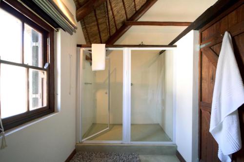 a glass shower in a bathroom with a window at Elands Bay Beach Villa in Elands Bay