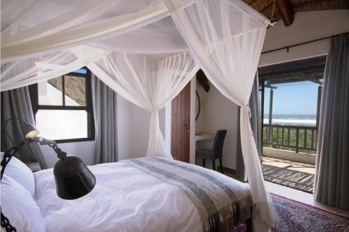 a bedroom with a canopy bed with a view of the ocean at Elands Bay Beach Villa in Elands Bay