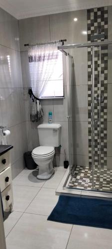 a bathroom with a toilet and a glass shower at Le Clus Stay in Bloemfontein