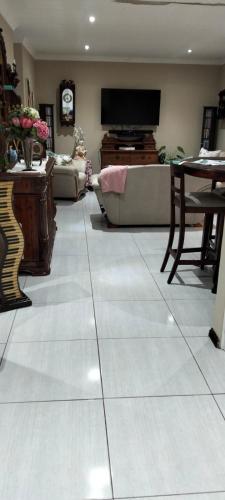 a living room with a tiled floor with a television at Le Clus Stay in Bloemfontein