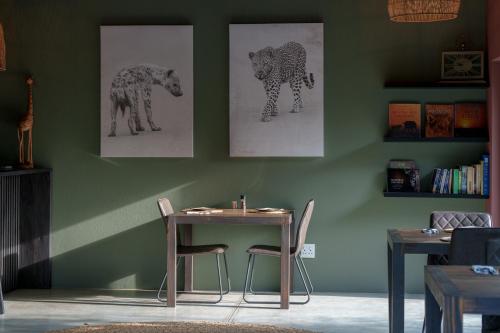 a table and chairs in a room with paintings on the wall at Taaibos Bush Lodge in Hoedspruit