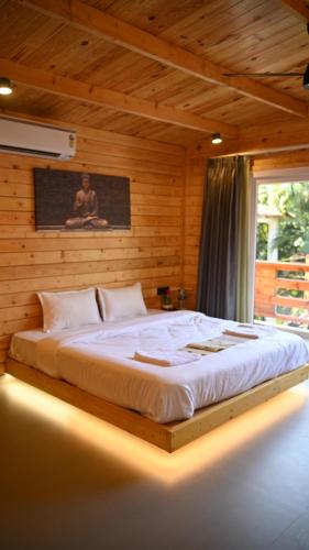 a bedroom with a large bed in a wooden wall at Tranquillo By The Beach, Candolim in Candolim