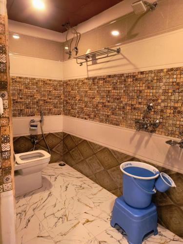 a bathroom with a toilet and a bucket on the floor at Namaste Benares Varanasi in Varanasi