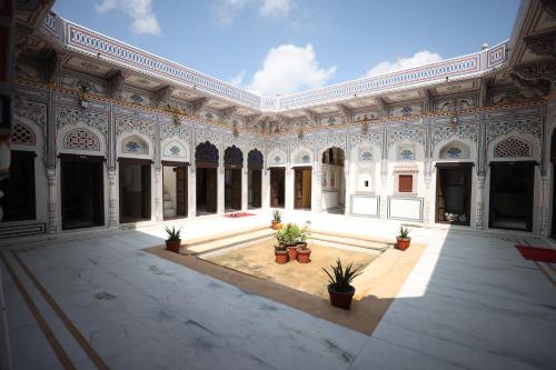 a large building with a courtyard with potted plants at Haveli Kesar Vilas in Chāran ki Dhāni