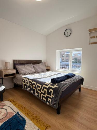 a bedroom with a bed and a clock on the wall at Modern East London Apartment with Private Studio & Guest Rooms-Near Bow, Victoria Park in London
