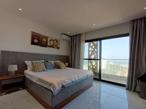 a bedroom with a bed and a large window at Ocean Waves Yoff Virage in Dakar
