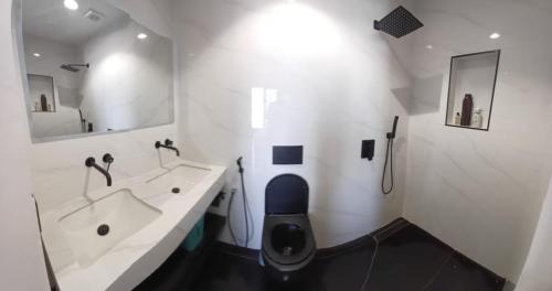 a white bathroom with a toilet and a sink at Ocean Waves Yoff Virage in Dakar