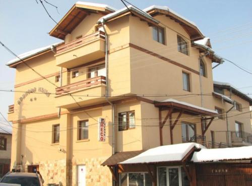 a building with snow on the ground in front of it at Hotel Boyanovi in Bansko
