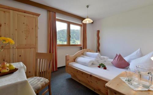 a bedroom with a wooden bed and a table and a window at Bauernhof Großwolfing- Appartementhaus Fischbacher in Ebbs